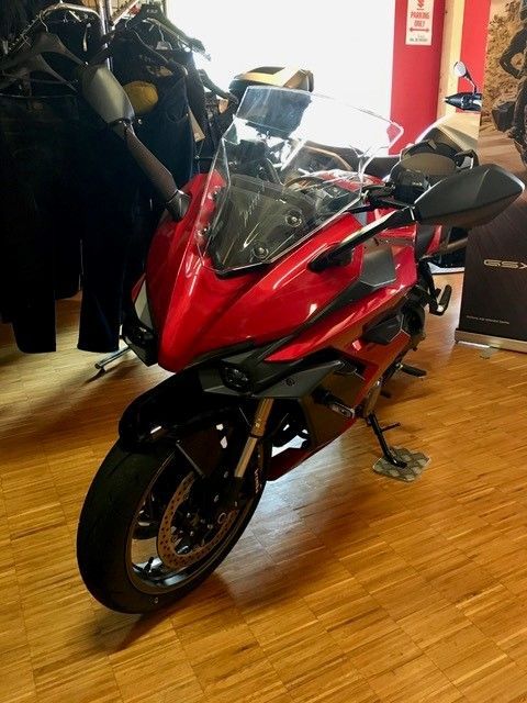 Ein rotes Motorrad ist auf einem Holzboden geparkt