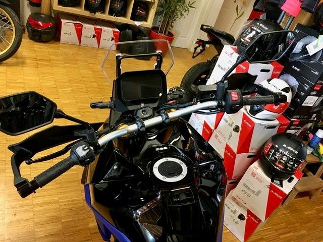 In einem Ausstellungsraum steht ein Motorrad neben Kisten voller Helme.