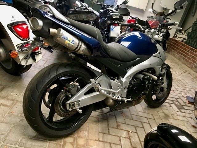 Ein blau-silbernes Motorrad ist auf einer gemauerten Auffahrt geparkt