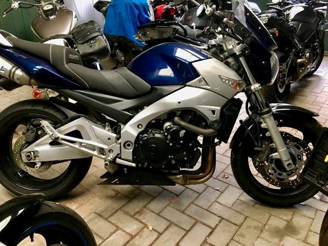 Ein blau-weißes Motorrad steht auf einem Parkplatz