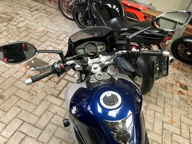 Ein blaues Motorrad ist auf einer gemauerten Auffahrt geparkt