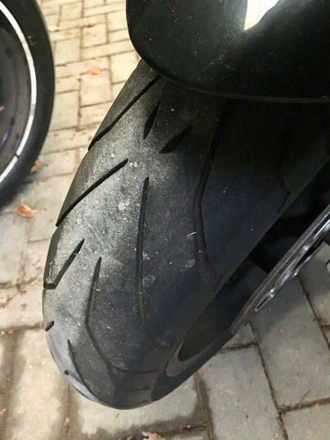 Eine Nahaufnahme eines Motorradreifens auf einem gepflasterten Gehweg.