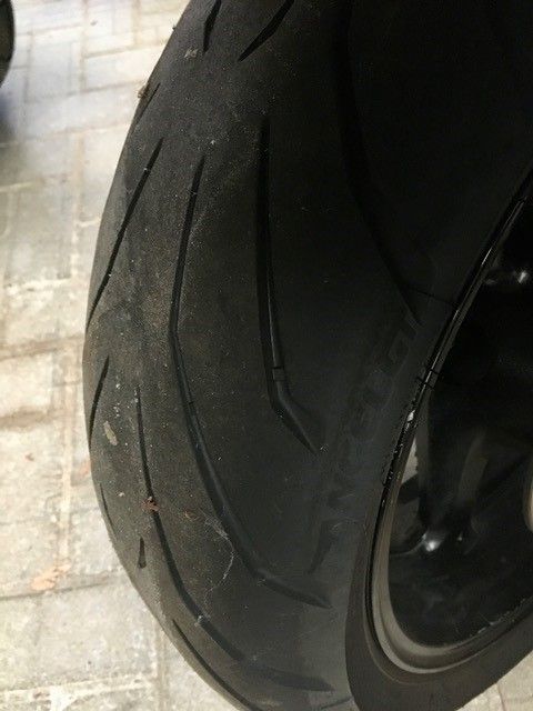 Eine Nahaufnahme eines Motorradreifens auf einer Ziegelsteinstraße.