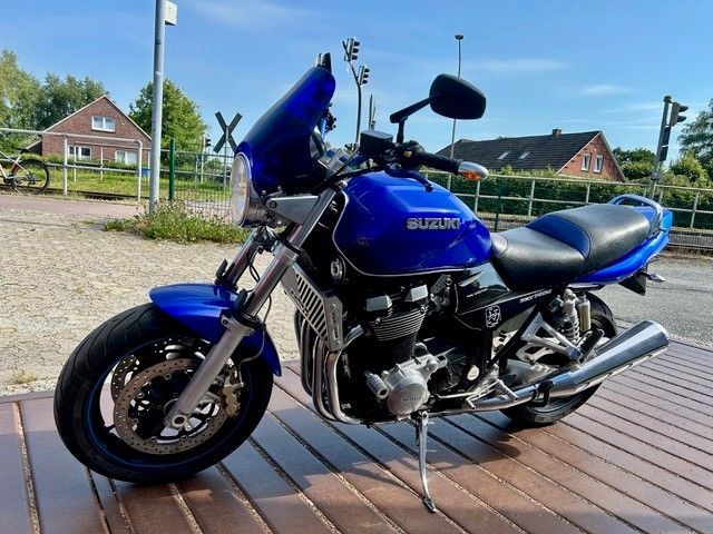 Ein blaues Suzuki-Motorrad steht an einem sonnigen Tag draußen auf einer Holzterrasse.