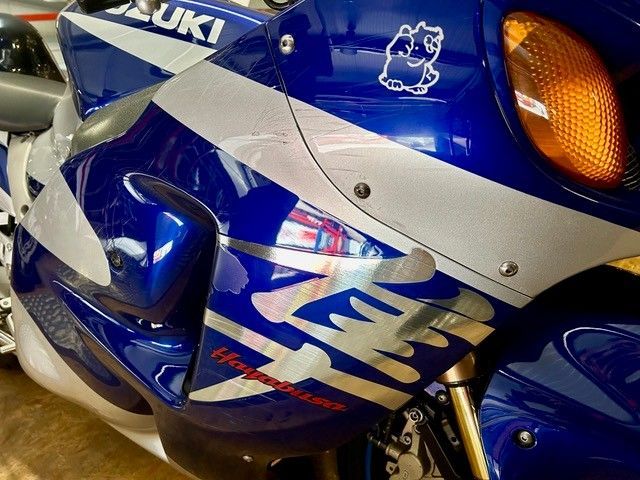 Blaue und weiße Suzuki-Motorradverkleidung mit orangefarbenen Blinkern und Rennaufklebern, Nahaufnahme