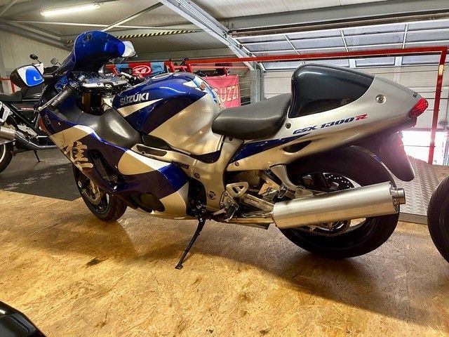Blau-silbernes Suzuki-Sportmotorrad in einer Garage, Seitenansicht.