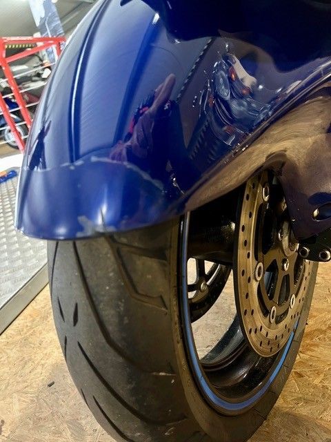 Vorderansicht des Vorderreifens und des Kotflügels eines blauen Sportmotorrads in einer Garage