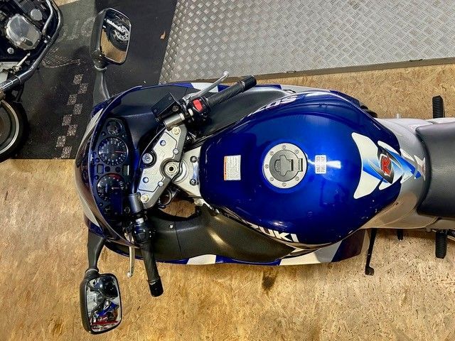 Blaues Motorrad, von oben betrachtet, in einer Halle geparkt; der silberne Tank und die Seitenspiegel sind sichtbar.