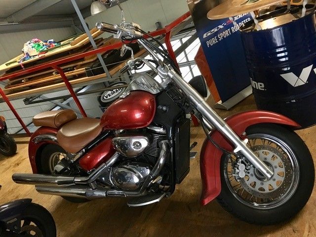 Ein rotes Motorrad steht neben einem blauen Fass mit der Aufschrift „Fuel Sport“