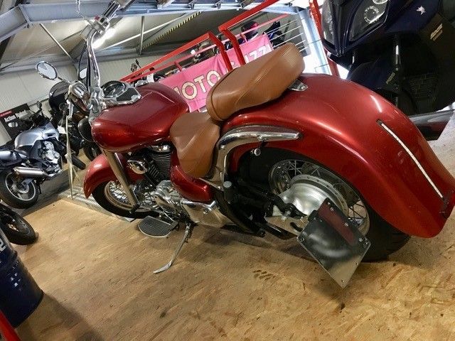 Ein rotes Motorrad mit braunem Sitz steht in einer Garage.