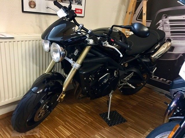 Ein schwarzes Motorrad ist in einem Raum neben einem Heizkörper geparkt