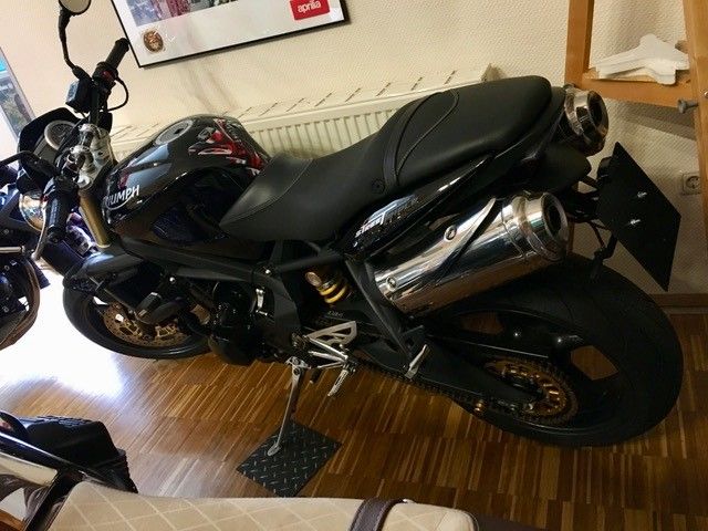 Ein schwarzes Motorrad ist auf einem Holzboden geparkt