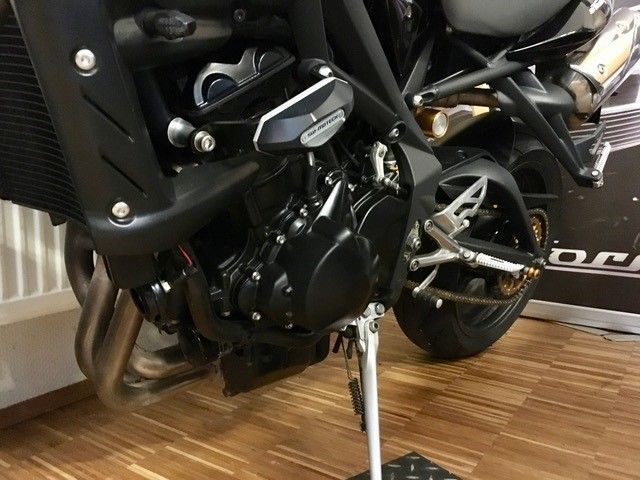 Ein schwarzes Motorrad ist auf einem Holzboden geparkt.