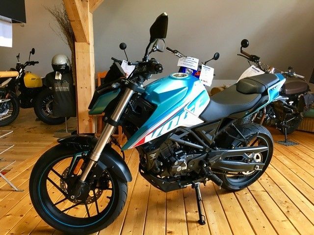 Ein blau-weißes Motorrad ist auf einem Holzboden geparkt