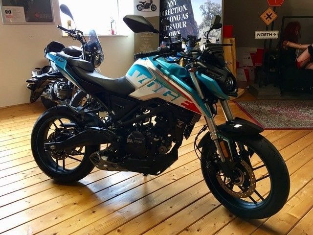 Ein blau-weißes Motorrad ist auf einem Holzboden geparkt