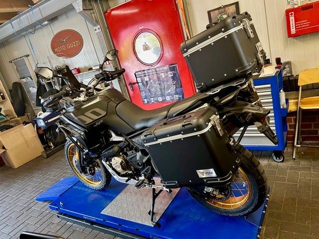 Schwarzes Tourenmotorrad mit Seitenkoffern auf einer blauen Hebebühne in einer Werkstattgarage