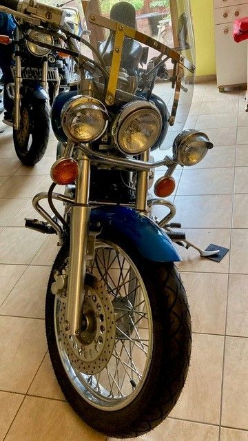 Ein blaues Motorrad mit Windschutzscheibe steht in einem Ausstellungsraum.