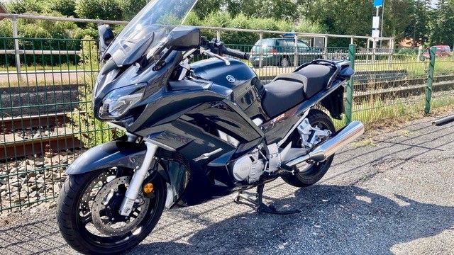 Ein Motorrad ist am Straßenrand neben einem Zaun geparkt.