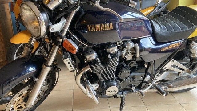 Auf einem gefliesten Boden ist ein blaues Yamaha-Motorrad geparkt.