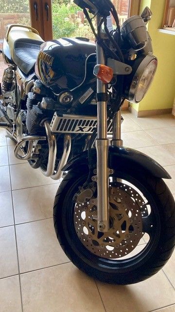 Ein schwarzes Motorrad ist auf einem gefliesten Boden in einem Raum geparkt.