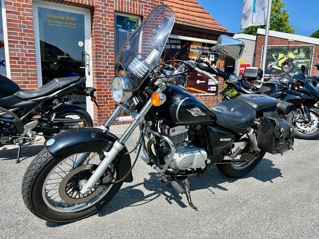 Vor einem Backsteingebäude parkt ein schwarzes Motorrad mit Windschutzscheibe.