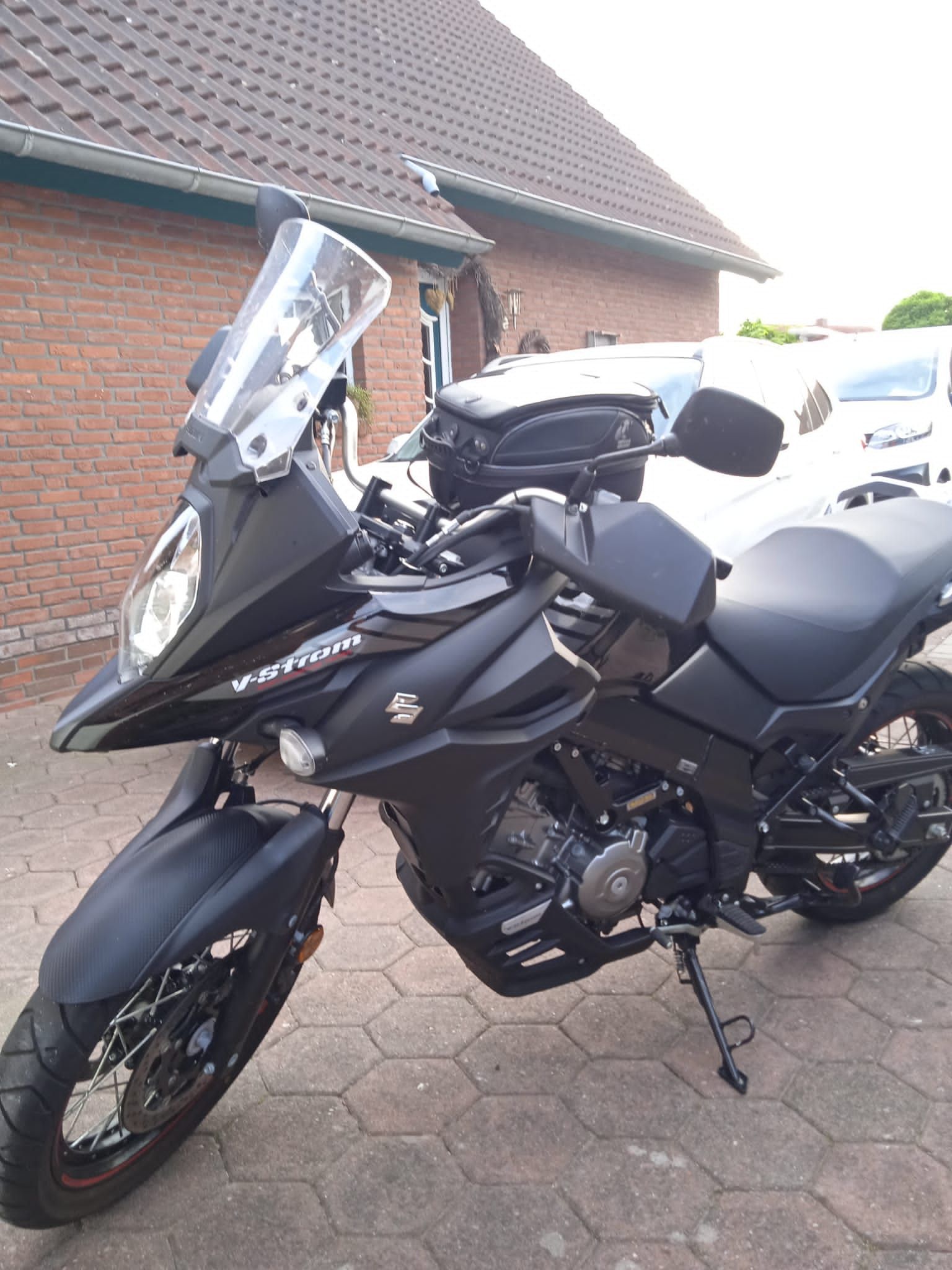 Vor einem Backsteingebäude parkt ein schwarzes Motorrad.