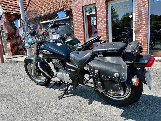 Vor einem Backsteingebäude parkt ein schwarzes Motorrad.