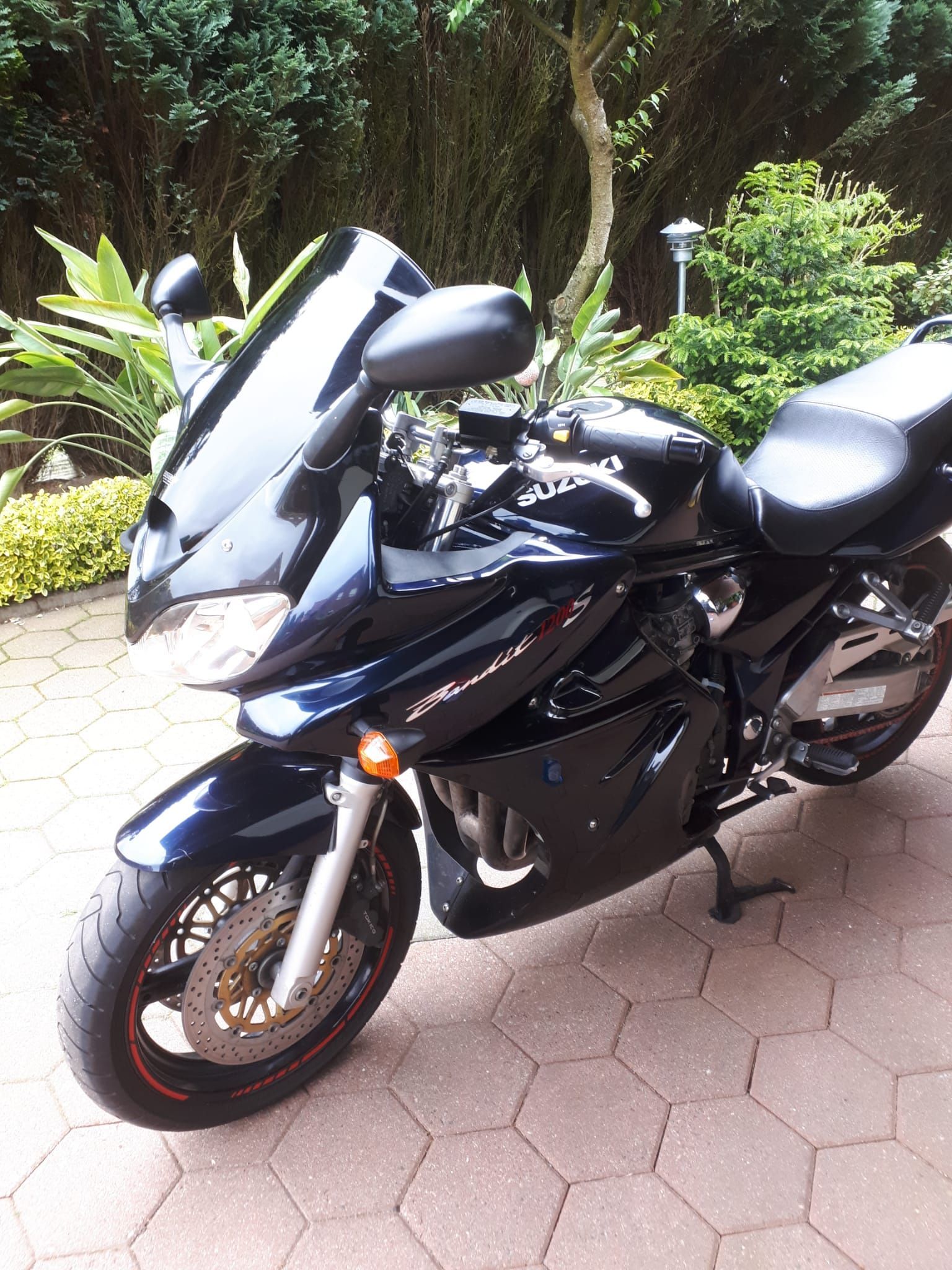 Ein schwarzes Motorrad ist auf einer gemauerten Auffahrt geparkt