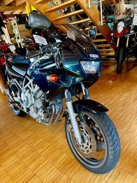 Ein Yamaha-Motorrad steht auf einem Holzboden in einer Garage.