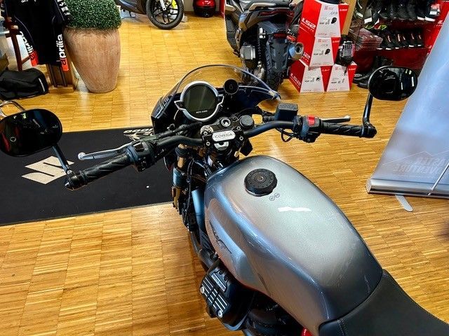 In einem Ausstellungsraum ist ein Motorrad auf einem Holzboden geparkt.