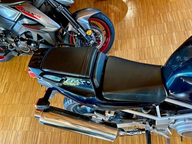 Ein Motorrad ist auf einem Holzboden neben einem anderen Motorrad geparkt.