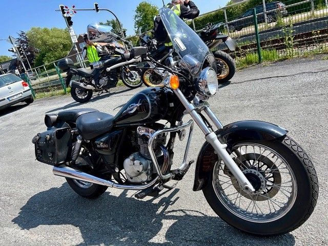 Ein schwarzes Motorrad mit Windschutzscheibe steht auf einem Parkplatz