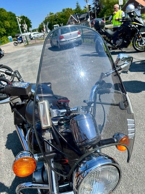 Ein Motorrad mit einer klaren Windschutzscheibe steht auf einem Parkplatz