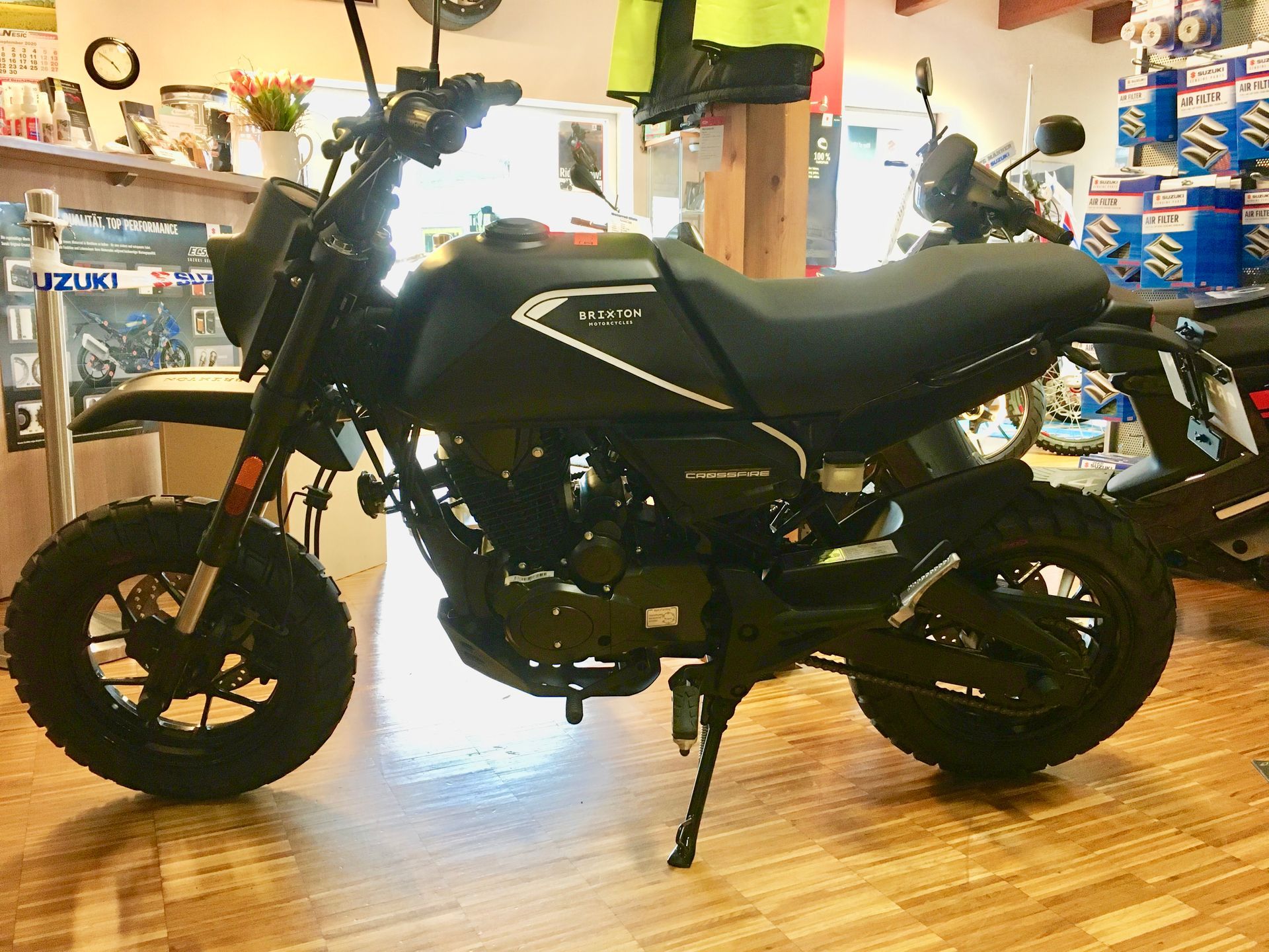 Ein schwarzes Motorrad steht auf einem Holzboden in einem Ausstellungsraum.