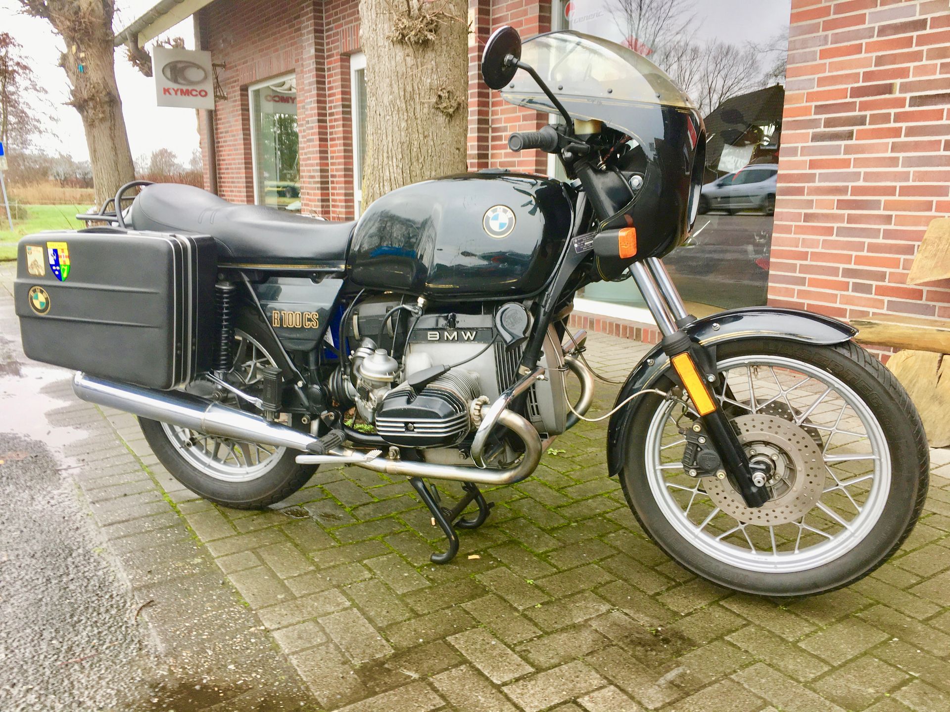 Vor einem Backsteingebäude parkt ein schwarzes Motorrad.