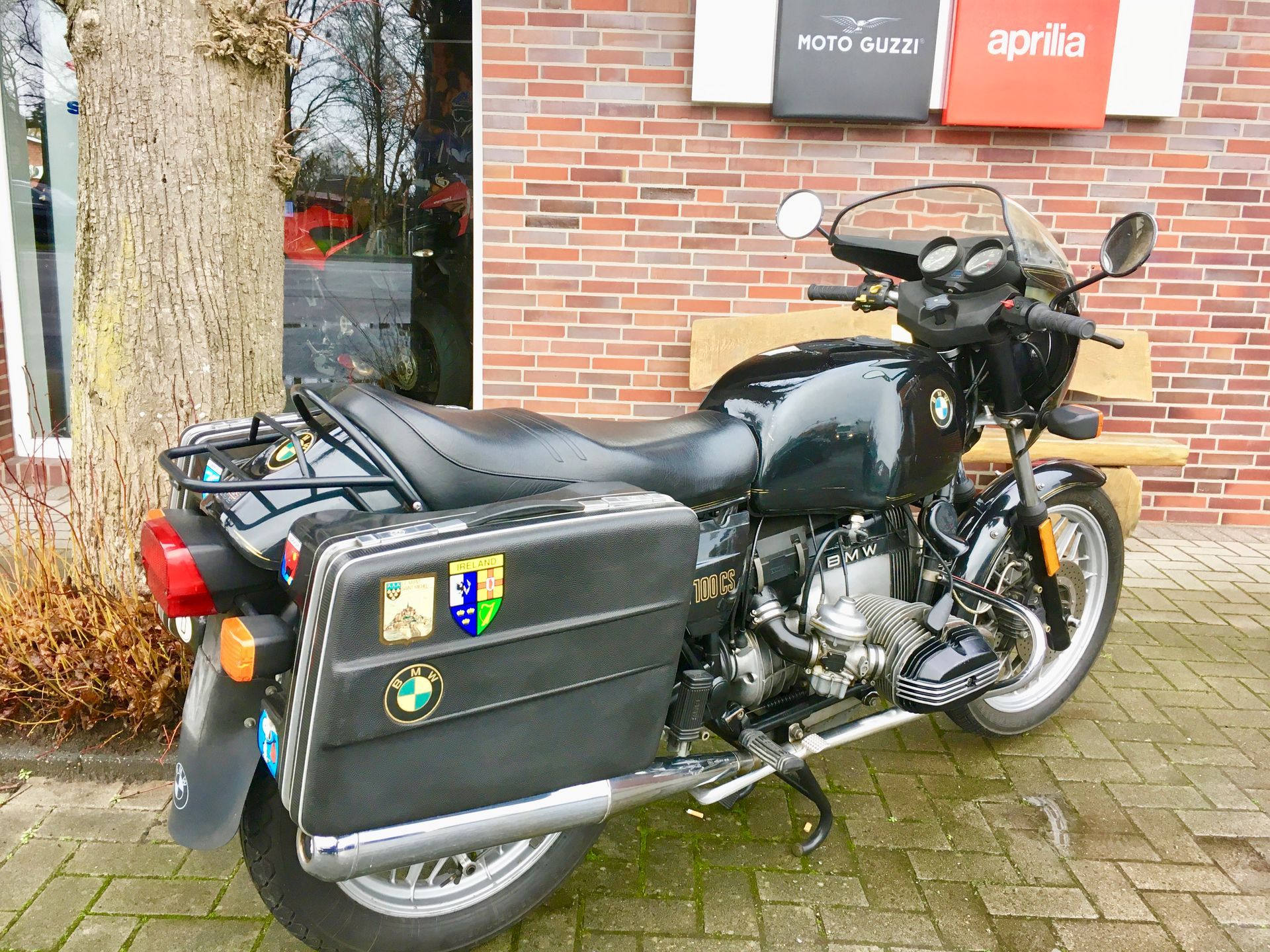 Vor einem Backsteingebäude parkt ein schwarzes Motorrad.