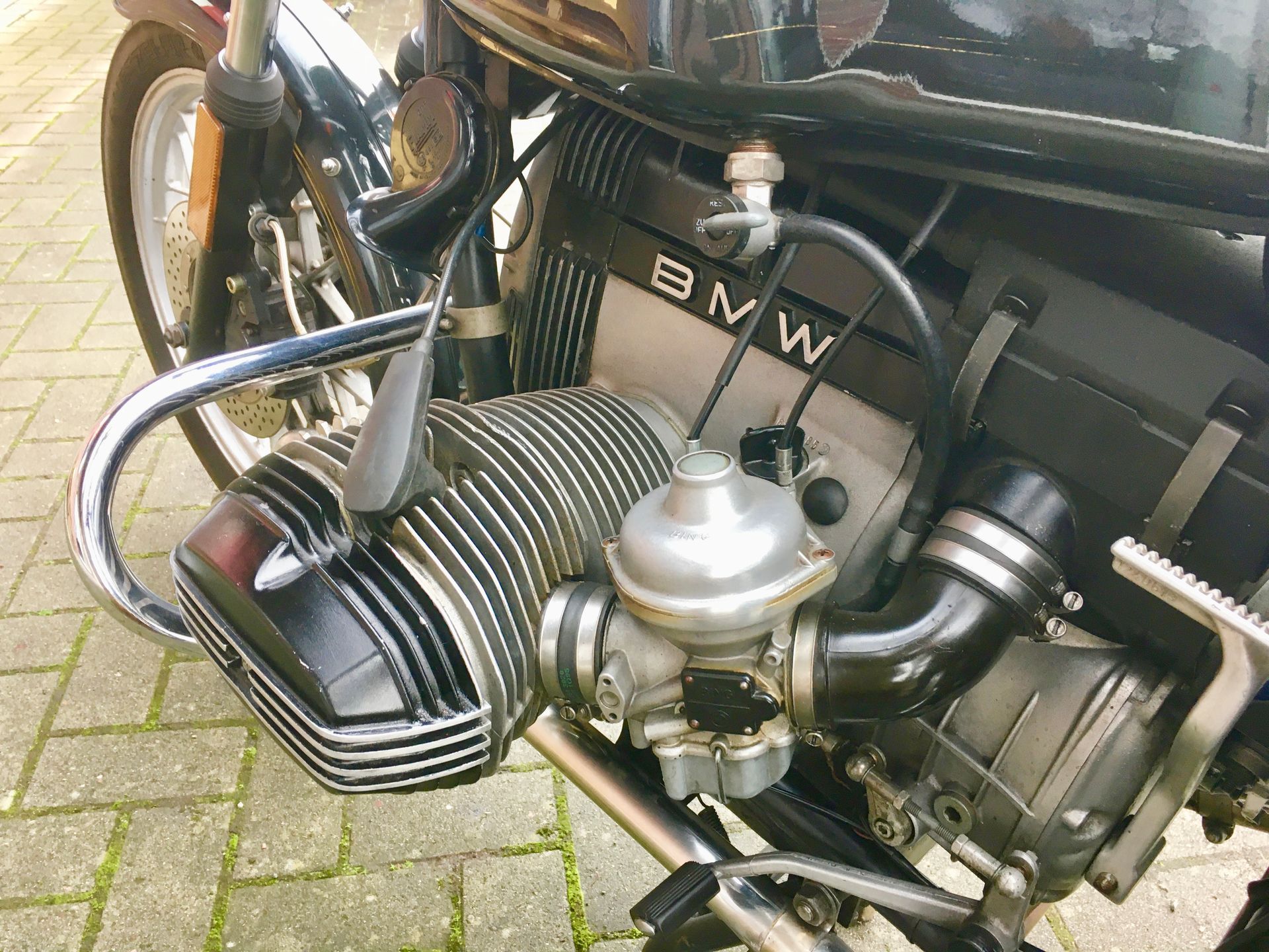 Eine Nahaufnahme eines BMW-Motorradmotors auf einem gepflasterten Gehweg.