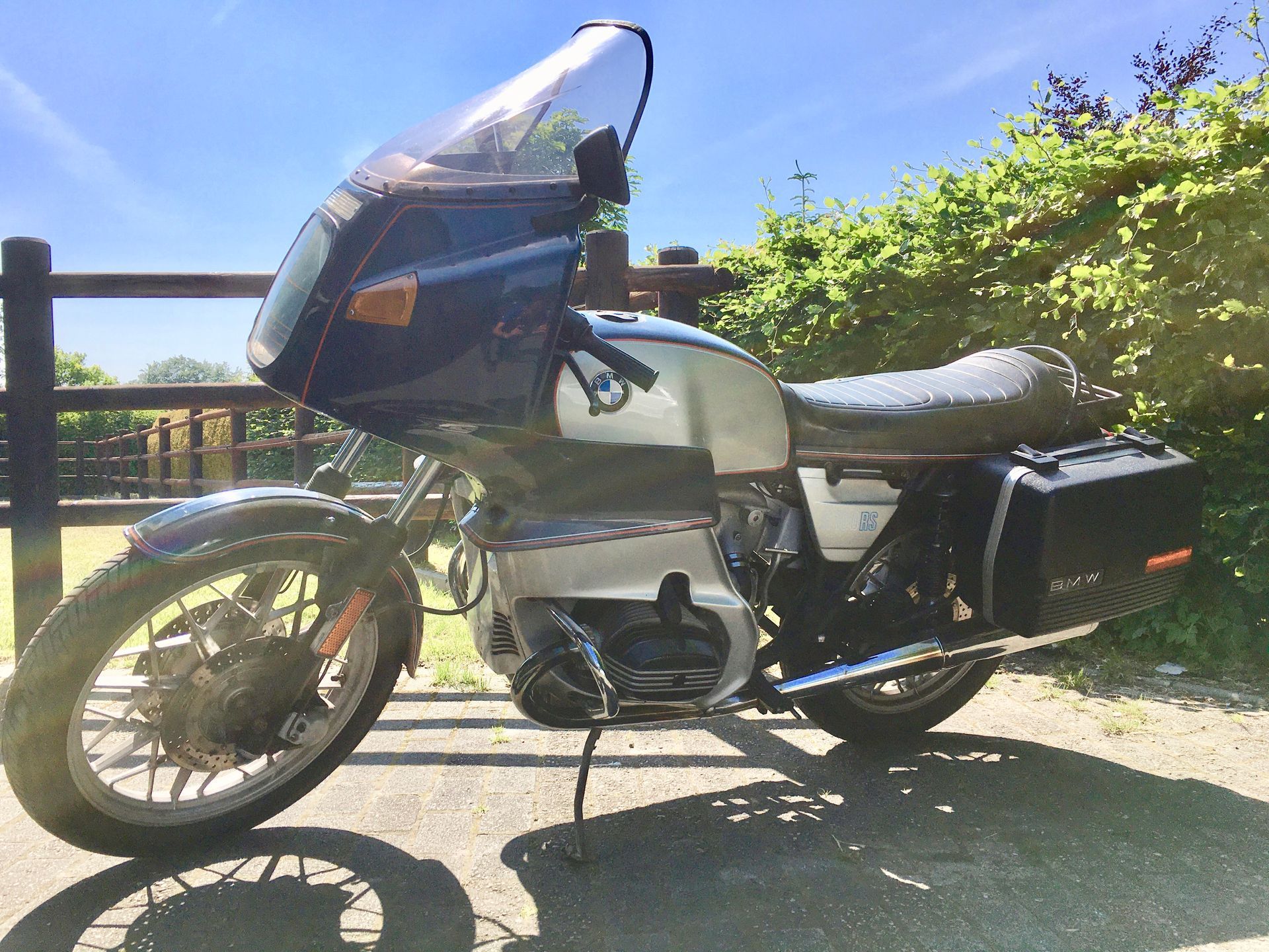 Ein Motorrad ist am Straßenrand vor einem Zaun geparkt.