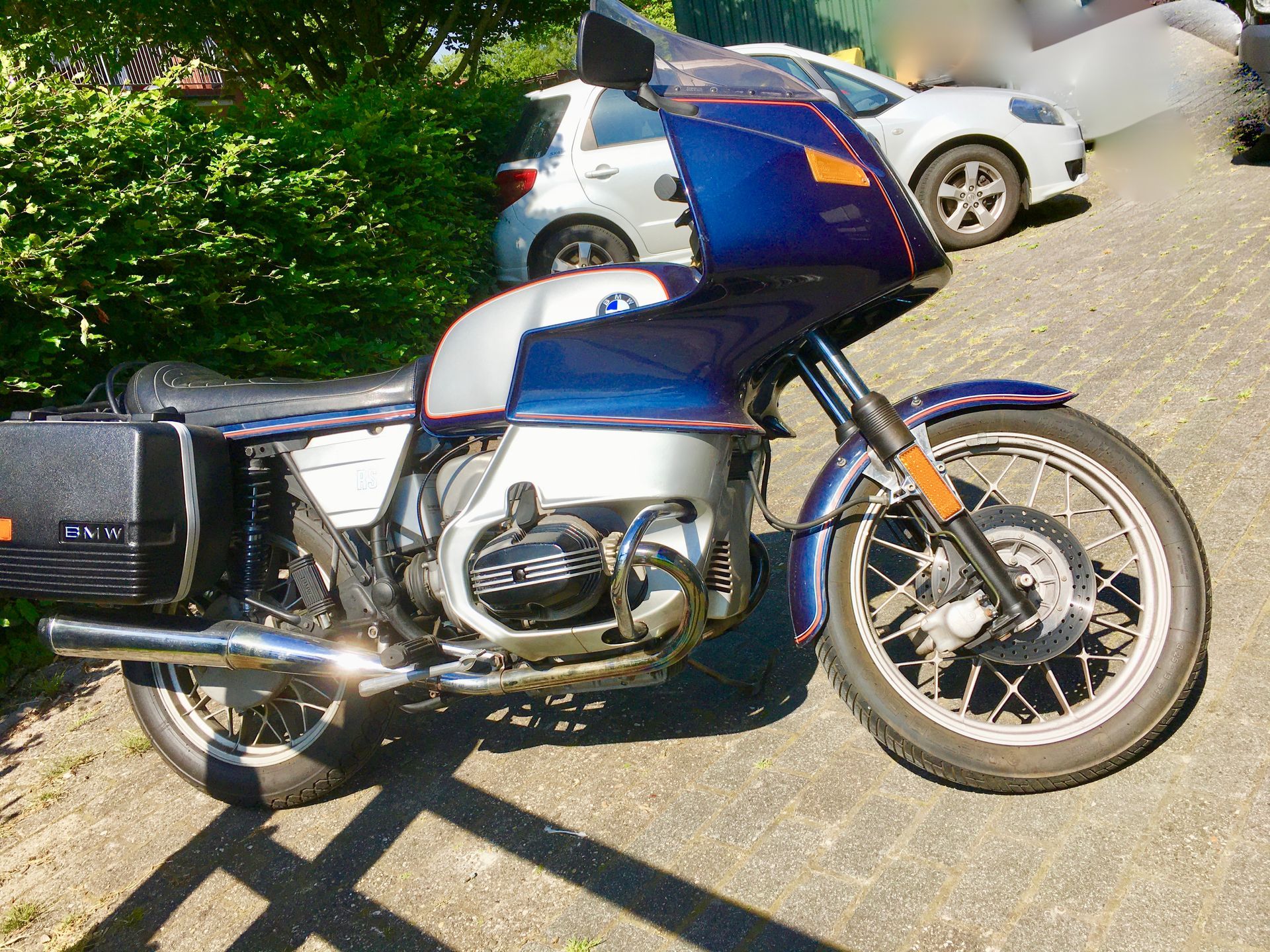 Ein blau-silbernes Motorrad steht am Straßenrand