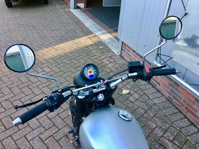 Auf einem gepflasterten Gehweg vor einem Gebäude ist ein Motorrad geparkt.