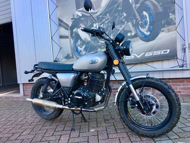 Vor einem Backsteingebäude ist ein Motorrad geparkt.