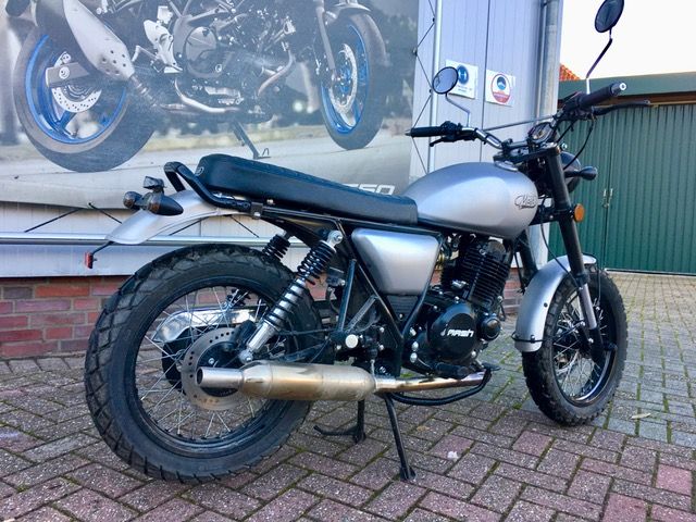 Auf einem gepflasterten Gehweg vor einem Gebäude ist ein Motorrad geparkt.