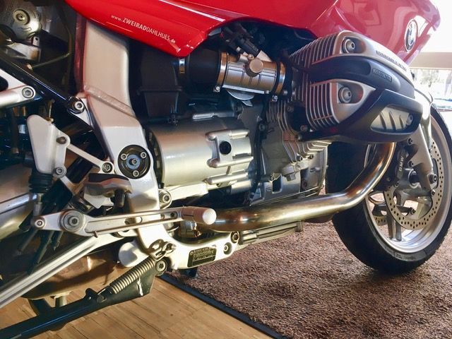 Ein rotes Motorrad ist auf einem Holzboden geparkt