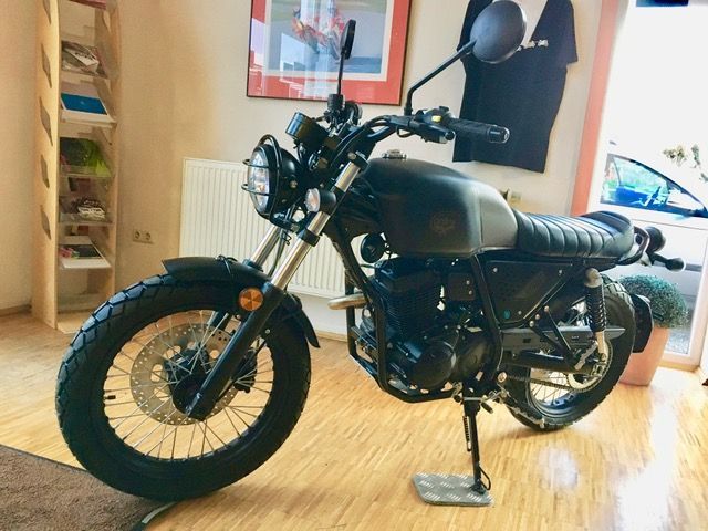 Ein schwarzes Motorrad ist auf einem Holzboden in einem Raum geparkt.