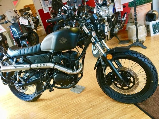 In einem Ausstellungsraum ist ein Motorrad auf einem Holzboden geparkt.