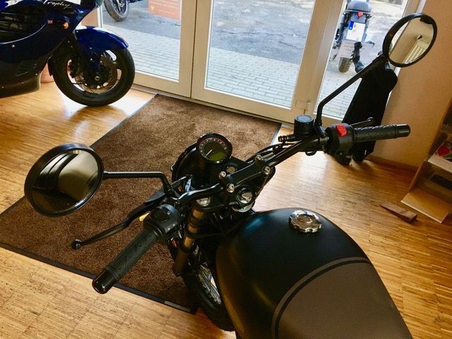 Ein schwarzes Motorrad ist in einem Raum mit anderen Motorrädern geparkt