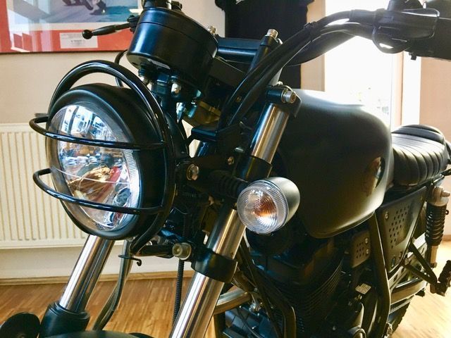 Ein schwarzes Motorrad ist auf einem Holzboden geparkt