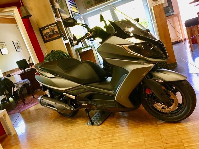 Ein Motorroller steht auf einem Holzboden in einem Raum.