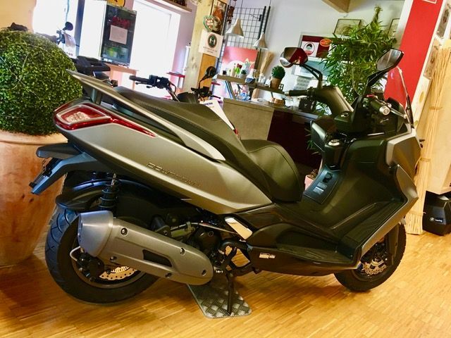 Ein Motorroller steht auf einem Holzboden in einem Raum.