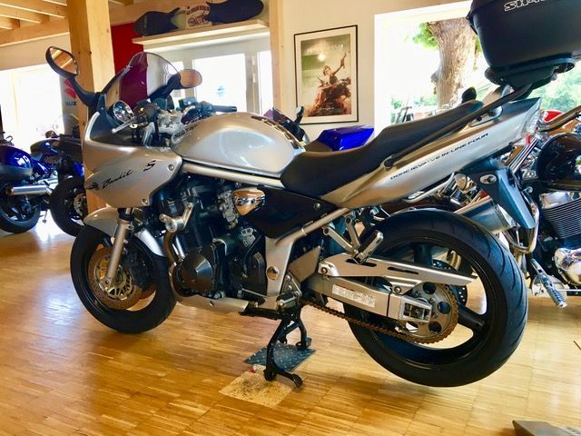 Ein silbernes Motorrad ist in einem Raum mit anderen Motorrädern geparkt.